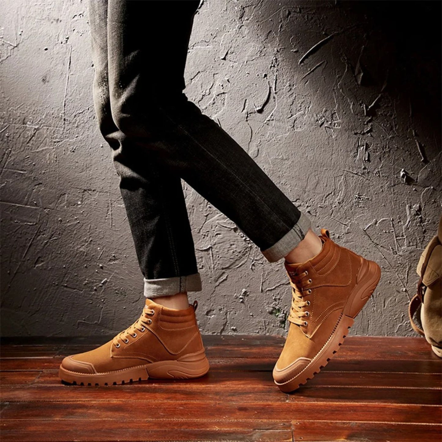 Person wearing brown winter boots with rolled-up pants, walking on wooden floor.