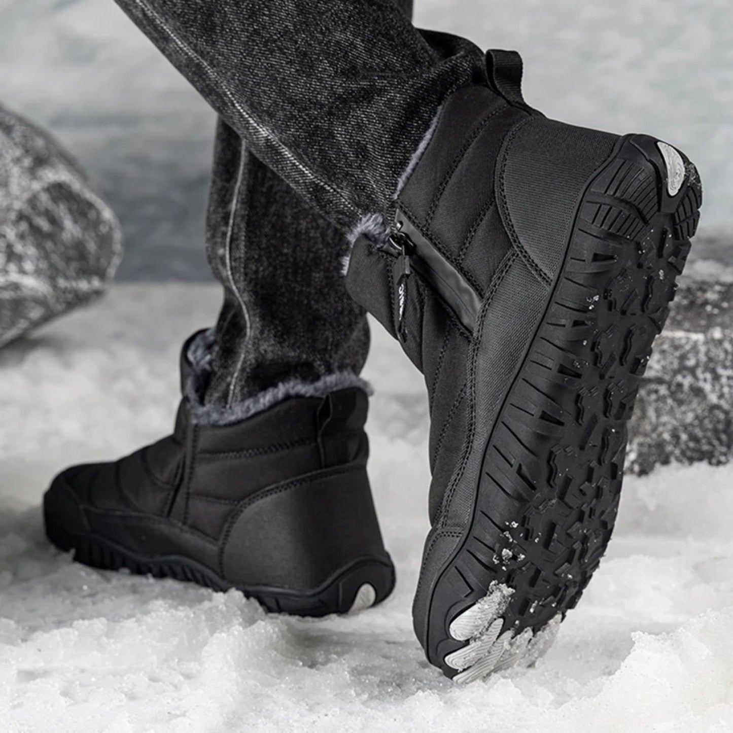 Person wearing black ankle boots with thick traction sole, walking in snowy setting.