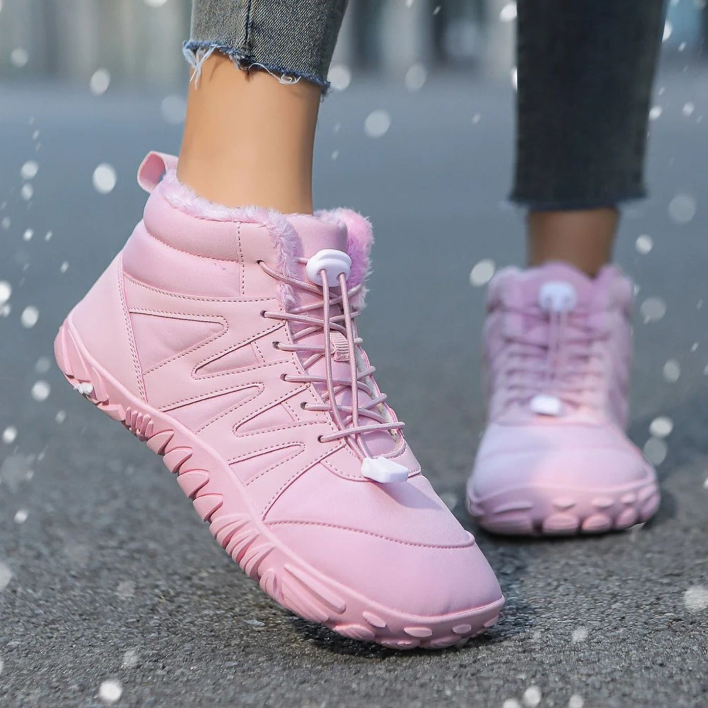 Pink winter boots with fleece lining worn in light snow, paired with jeans.