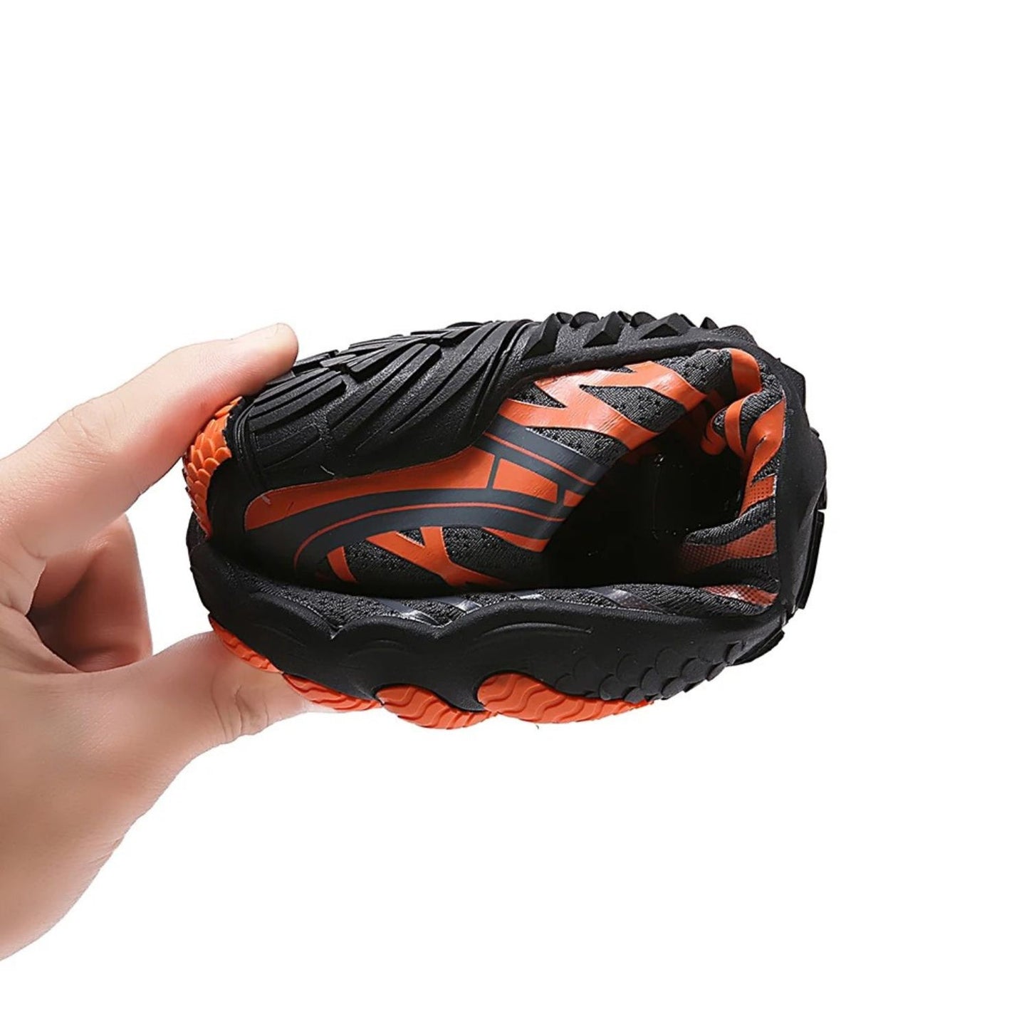 Black barefoot shoe with orange sole fully rolled up for compact storage.