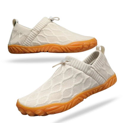 White slip-on casual shoe with textured pattern and orange sole, side profile.