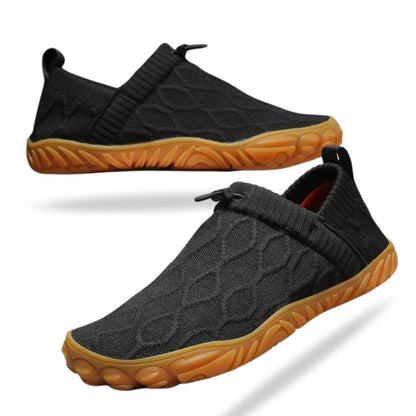 Black slip-on shoe with quilted upper and bright orange sole, side angle view.