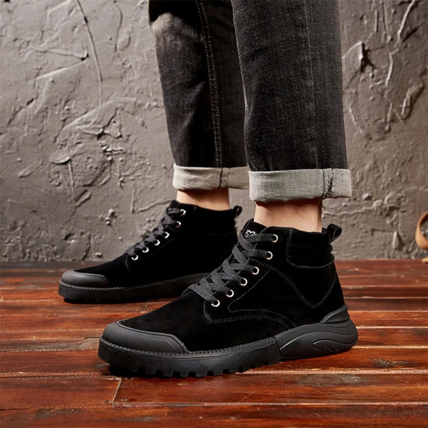 Black winter boots worn with cuffed jeans, shown in motion on wood flooring.