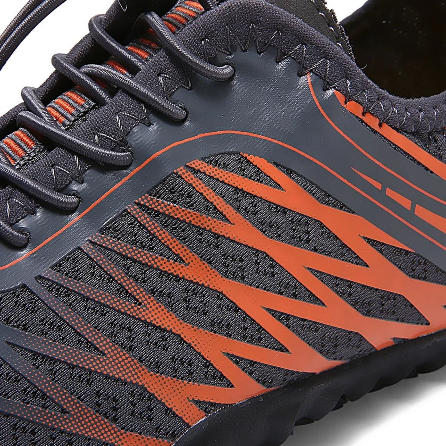 Detailed side view of black barefoot shoe with orange mesh stripes and lace stitching.