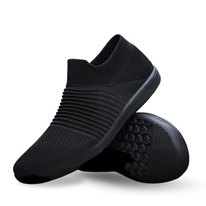 Black slip-on knit sneaker with ribbed texture, shown with flexible outsole detail.
