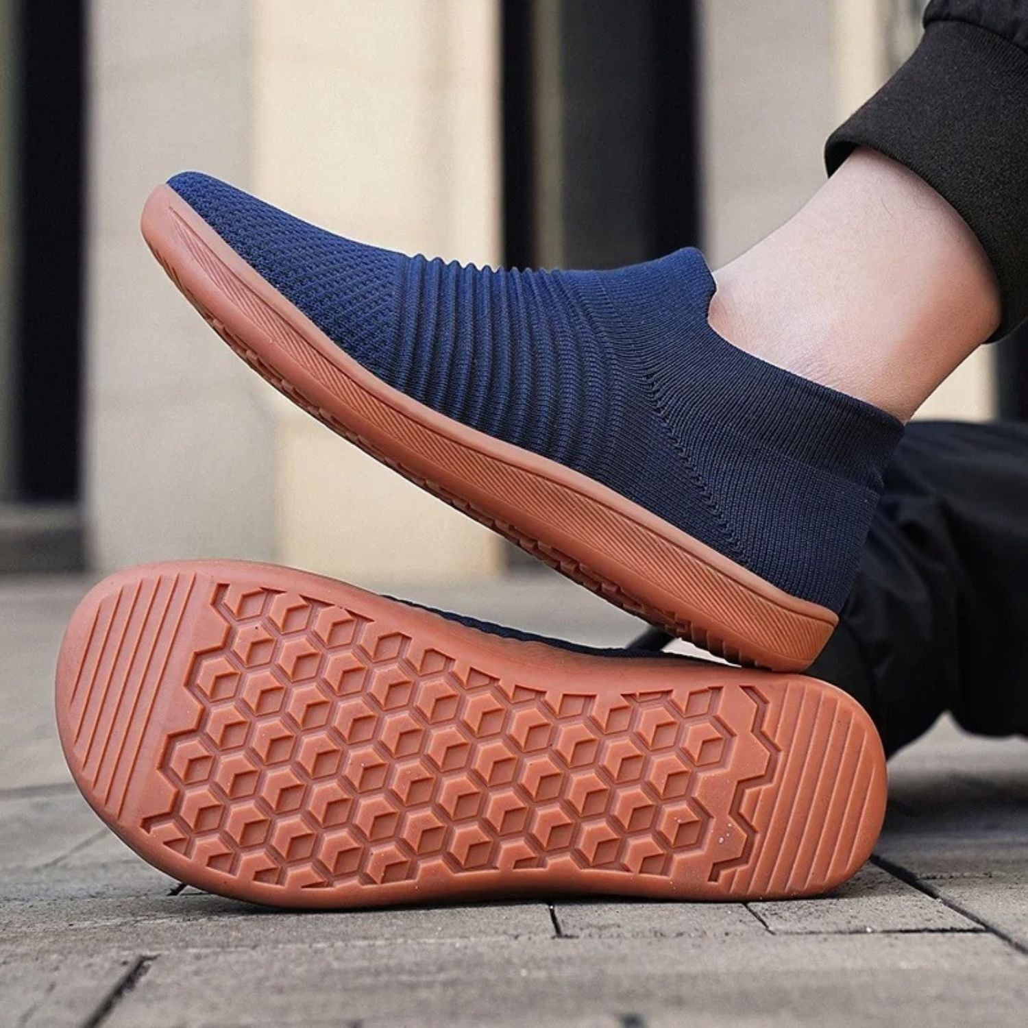 Navy blue slip-on sneakers worn outdoors, showing brown textured sole.