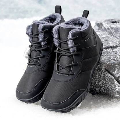 Pair of black winter boots with fleece lining displayed on snow-covered rock.